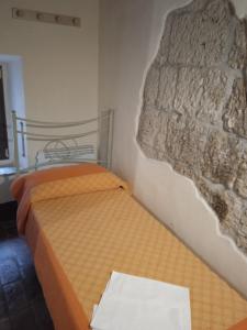 een bed in een kamer met een stenen muur bij La casa di Iara in Pitigliano