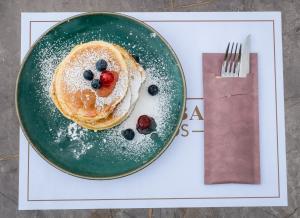 a green plate with pancakes and berries on a table at Green Bay in Limenaria