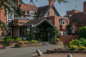 duży budynek ceglany z roślinami przed nim w obiekcie Chesford Grange Hotel w mieście Kenilworth