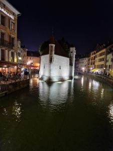 a building in the middle of a river at night at Face au Lac in Annecy