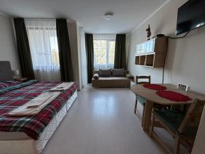 a bedroom with a bed and a table and a couch at Borovets Gardens Funky Fresh Studio by Joro in Borovets