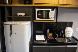 a kitchen with a microwave and a refrigerator and a sink at Studio no centro de Curitiba in Curitiba