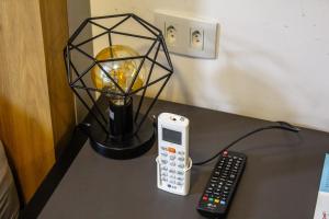 a table with a phone and a lamp and a remote control at Studio no centro de Curitiba in Curitiba