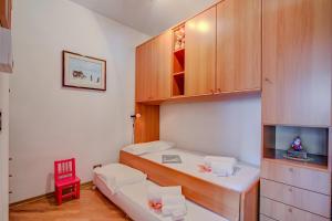 ein kleines Zimmer mit 2 Betten und einem roten Stuhl in der Unterkunft Snow White - Happy Rentals in Bardonecchia