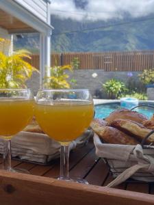 Dois copos de sumo de laranja e pão numa mesa. em Villa Ananda em Cilaos