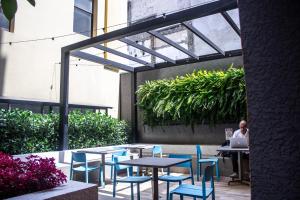 a patio with tables and chairs and a person sitting at a laptop at Studio no centro de Curitiba in Curitiba