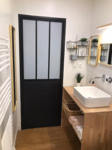 La salle de bains est pourvue d'une porte noire et d'un lavabo. dans l'établissement LE JARDIN D'ALEXANDRE, à Orléans