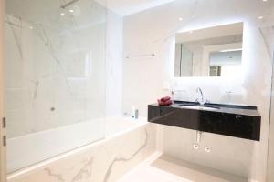 een badkamer met een wastafel, een bad en een spiegel bij Scuol Palace Bed & Breakfast in Scuol
