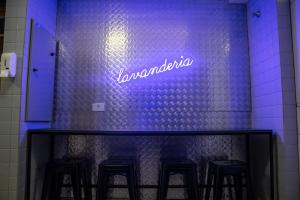 a neon sign on a wall with some bar stools at Studio no centro de Curitiba in Curitiba