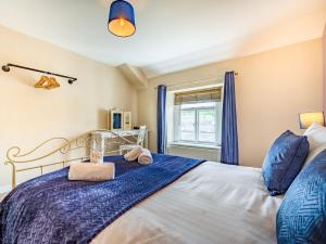 een slaapkamer met een bed met blauwe lakens en een raam bij 2 Bed in Cockermouth 87481 in Cockermouth
