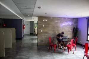 a man sitting at a table with a laptop at Studio no centro de Curitiba in Curitiba