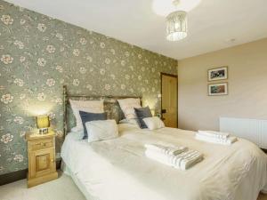 1 dormitorio con 1 cama blanca grande y papel pintado con motivos florales en 1 bed in Barnstaple 88259, 
