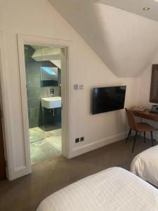 a bedroom with a bathroom with a sink and a tv at The Rooms Lytham in Lytham St Annes