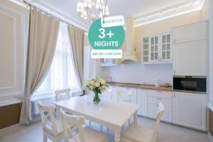 cocina blanca con mesa blanca y sillas en Revelton Suites Karlovy Vary, en Karlovy Vary