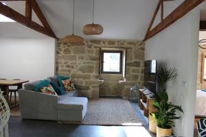 - un salon avec un canapé et un mur en pierre dans l'établissement Casas Velhas, à Santo Aleixo de Além Tamega