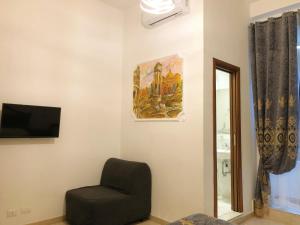 een kamer met een stoel, een schilderij en een spiegel bij Hostel Cosmos in Rome