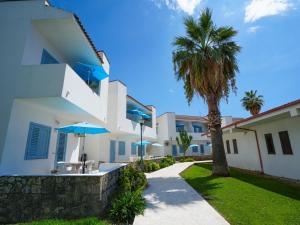 a white house with a palm tree and a sidewalk at Villaggio Residence Bahja in Paola