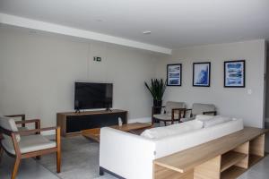a living room with a white couch and a tv at Studio no centro de Curitiba in Curitiba