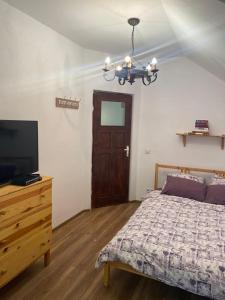 1 dormitorio con 1 cama, TV y lámpara de araña en Trei Tulnice, en Rau Sadului