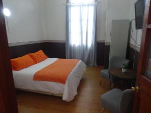1 dormitorio con cama, ventana y mesa en Gran Casona Hostal, en Iquique