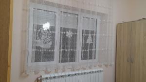 uma janela com cortinas de renda branca e um radiador em Apartman Visnja em Rudnik