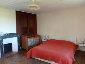 1 dormitorio con cama roja y chimenea en Le Chapelat, en Saint-Michel-Saint-Jaymes