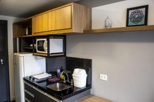 a kitchen with a sink and a microwave at Studio no centro de Curitiba in Curitiba