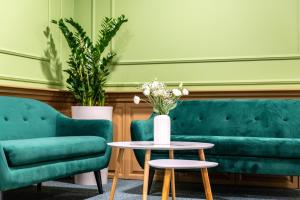 a living room with two green chairs and a table at Dnipro Hotel in Kyiv