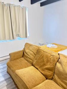 eine Couch in einem Wohnzimmer neben einem Fenster in der Unterkunft Ebehi Inn in London