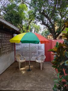 einen Tisch mit einem bunten Regenschirm und zwei Stühlen in der Unterkunft Rosetta Guesthouse in Anjuna