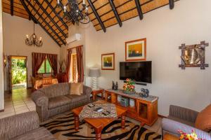 uma sala de estar com sofás e uma televisão em Kruger Park Lodge Unit No. 516 em Hazyview