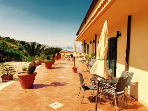 un patio con sillas y una mesa con sombrilla en Villa della Mimosa, en Alia