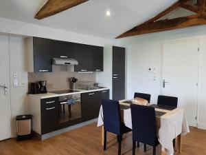 een keuken met een tafel en blauwe stoelen in een kamer bij La Mariennaye in Beaurepaire