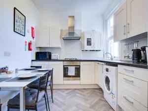 a kitchen with white cabinets and a table with chairs at Pass the Keys Comfortable flat near Southend in Westcliff-On-Sea