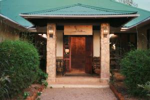 una casa con techo verde y puerta de madera en Hidden Valley Wilderness Lodge en San Ignacio