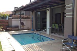 a swimming pool with a swing and a house at Pecanwood Estate Cosy home 3 bedrooms with pool in Hartbeespoort