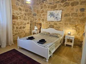 - une chambre avec un lit blanc dans un mur en pierre dans l'établissement Unique Farmhouse in the Heart of Gozo - Nadur, à In-Nadur