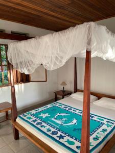 - une chambre avec un lit à baldaquin dans l'établissement Residence Monique, sur l'île aux Nattes
