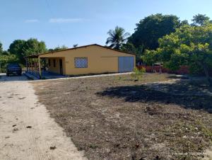 a small yellow building in the middle of a yard at Aconchego do bens in Cruz