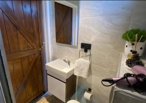 ein Badezimmer mit einem Waschbecken und einer Holztür in der Unterkunft Carpe Diem (Rose) in Şarköy