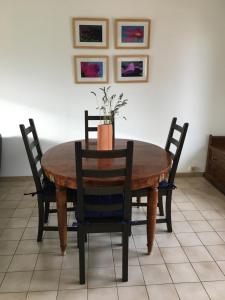 einen Holztisch mit Stühlen und eine Vase mit Blumen darauf in der Unterkunft Maison de vacances au calme in Angles