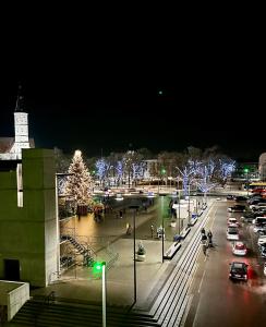 Una ciudad de noche con un árbol de Navidad en un estacionamiento en Butas pačiame Šiaulių miesto centre en Šiauliai