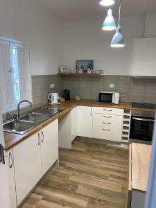 uma cozinha com armários brancos e piso em madeira em Casa da Bisa em Carreiras