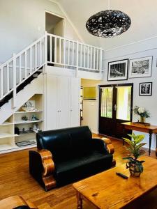 a living room with a black couch and a table at The Olive Tree Cottage in Riebeek-Wes