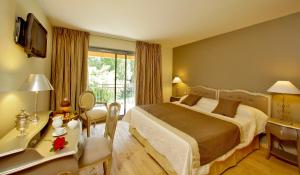 a hotel room with a bed and a desk and a bed and a room at Le Moulin de Mitou in Auriac-du-Périgord