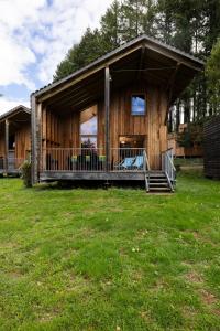 Cabaña de madera con porche y césped en Camping Le Lac des Sapins, en Cublize