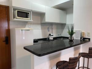 cocina con encimera negra y microondas en Apartamento Studio lado do Hospital Premium ST2203, en Goiânia