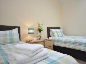 a bedroom with two beds and a table with a lamp at 2 Bed in Blakeney 54766 in Awre