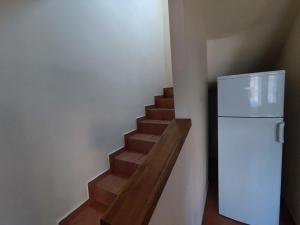 un escalier avec un réfrigérateur blanc et un escalier en bois dans l'établissement Váralja Vendégház, à Tata