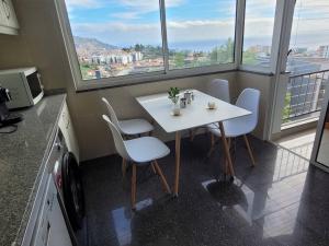 a white table and chairs in a kitchen with windows at Pilar Balconies in Funchal City in Funchal